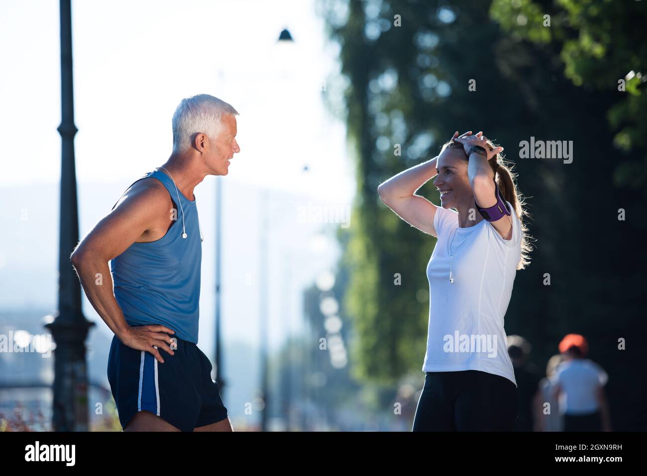 jogging couple check music playlist on phone and plan route before morning  running workout with sunrise in the city and sun flare in background Stock  Photo - Alamy