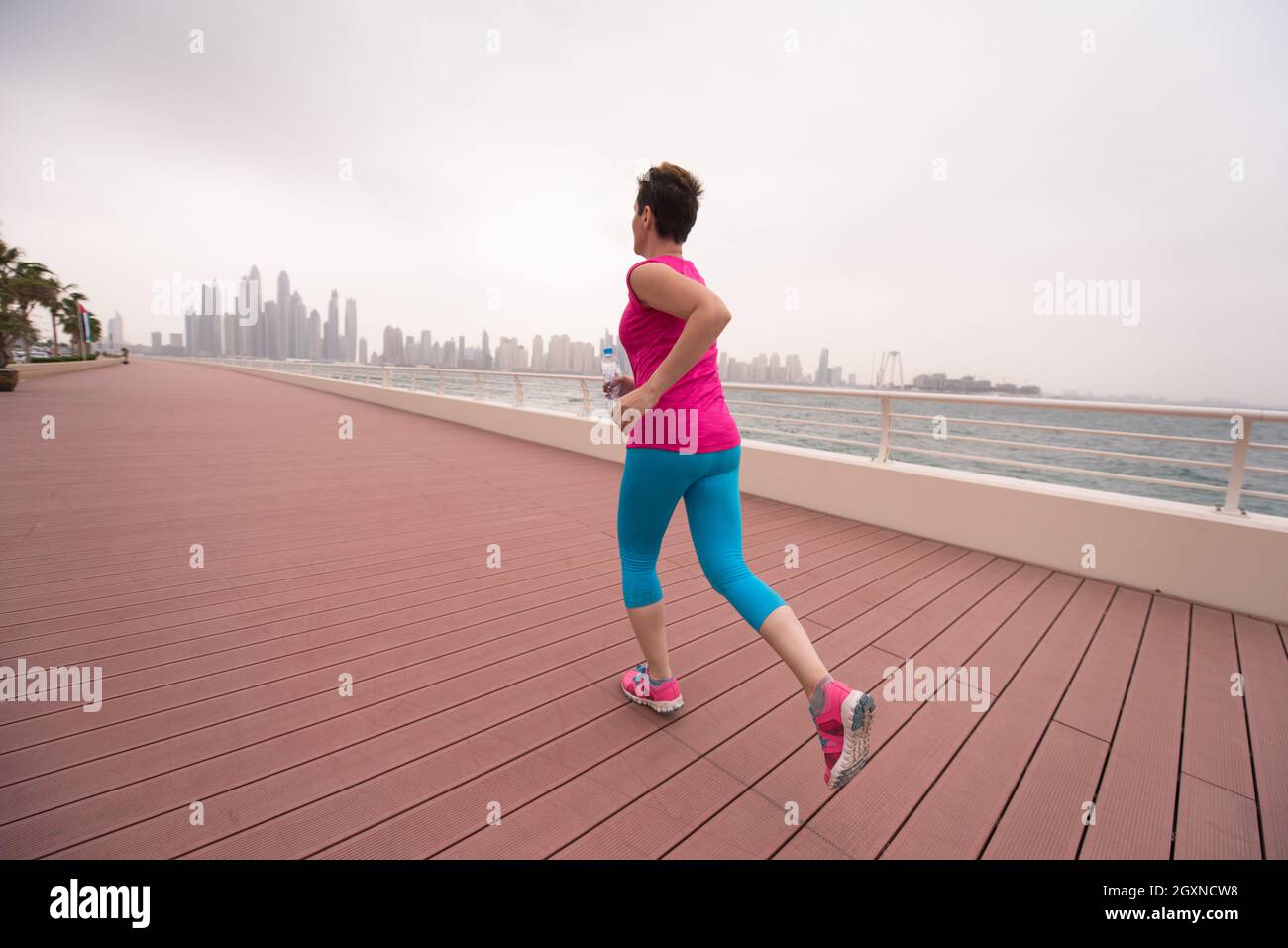 very active young beautiful woman busy running on the promenade along ...