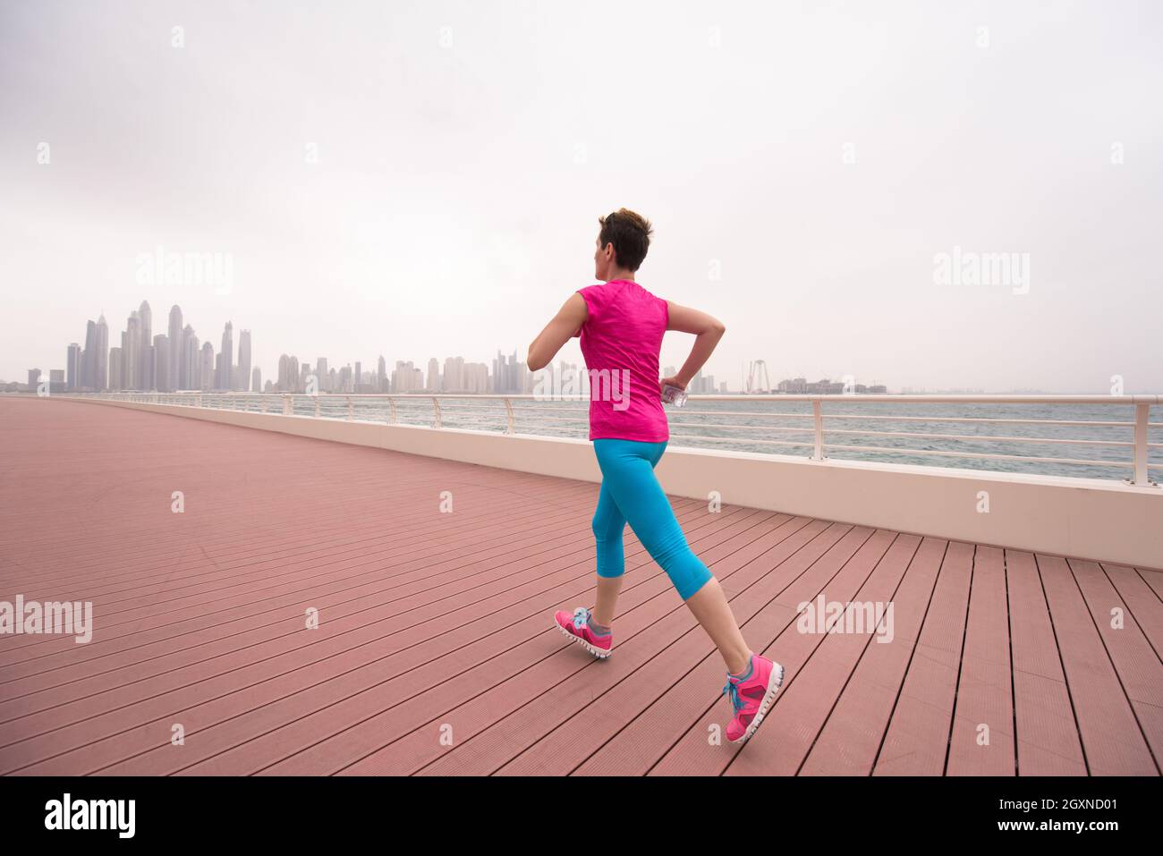 very active young beautiful woman busy running on the promenade along ...