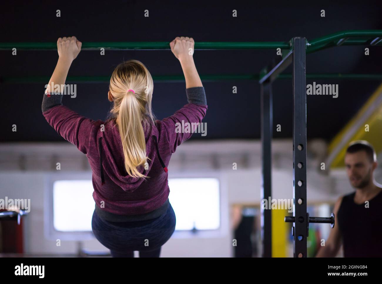 young muscular woman doing pull ups on the horizontal bar as part of ...