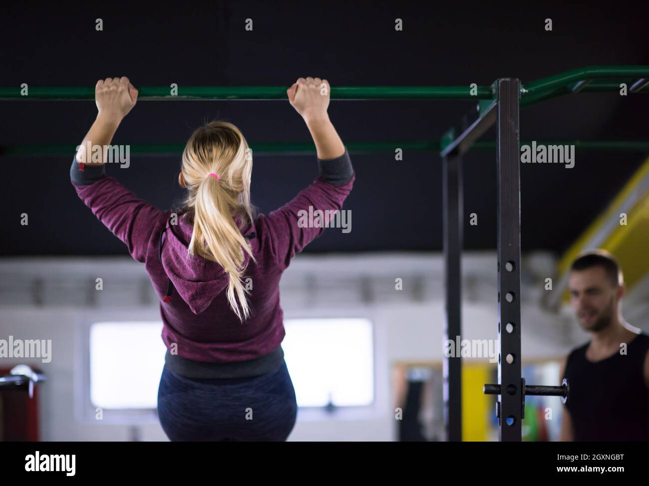young muscular woman doing pull ups on the horizontal bar as part of ...