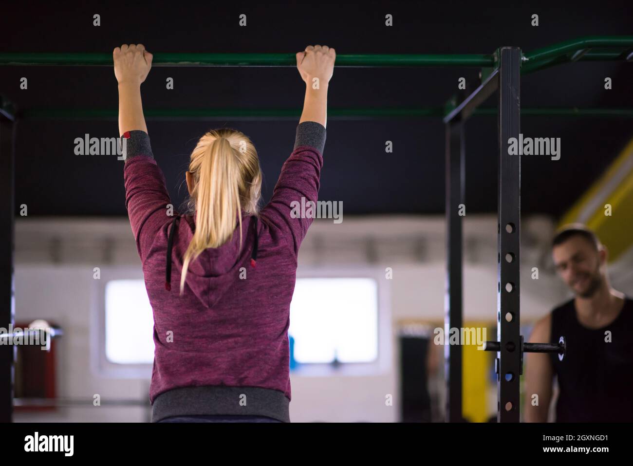 young muscular woman doing pull ups on the horizontal bar as part of ...