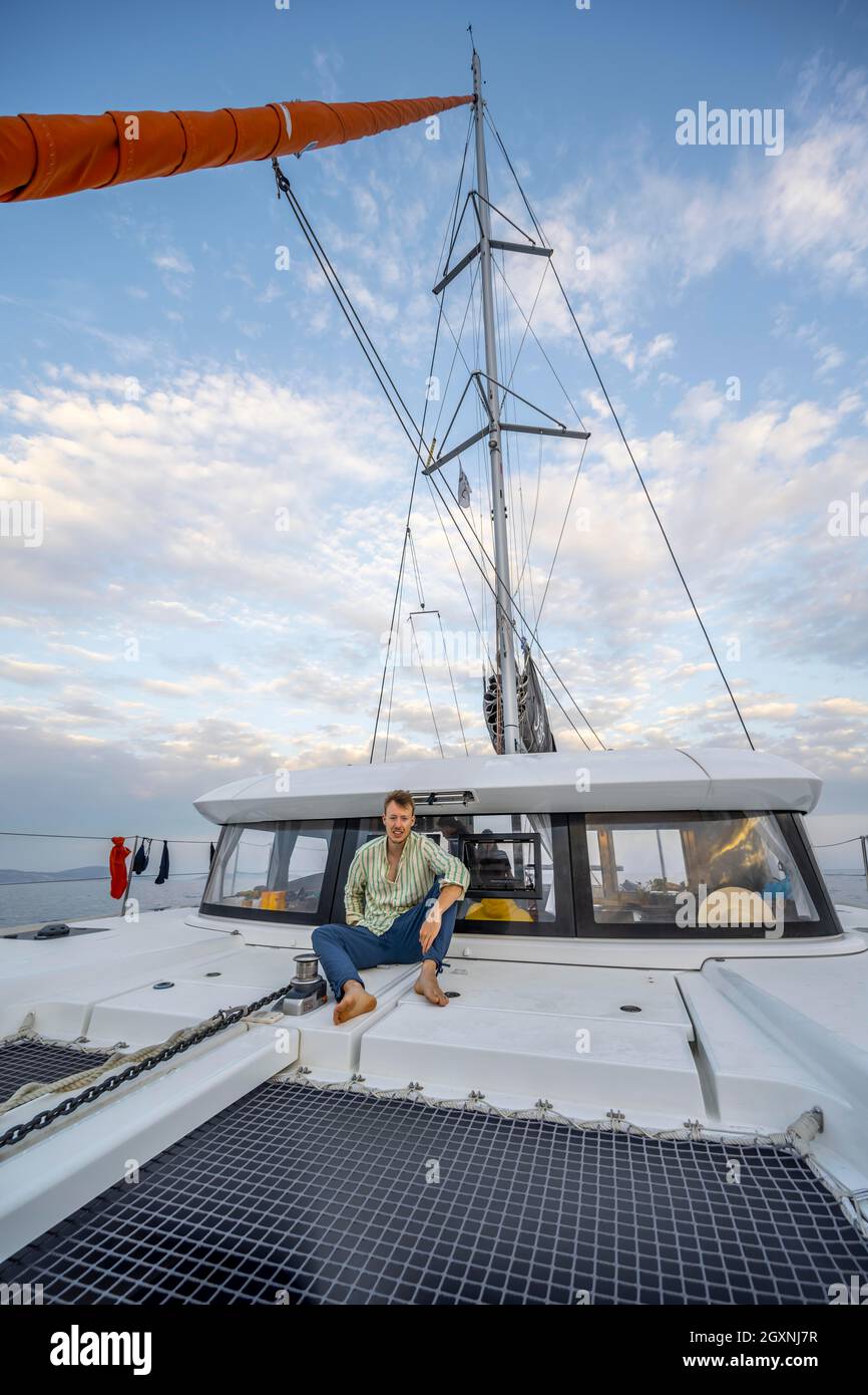 Young man sitting on the deck of a sailing catamaran, sailing trip