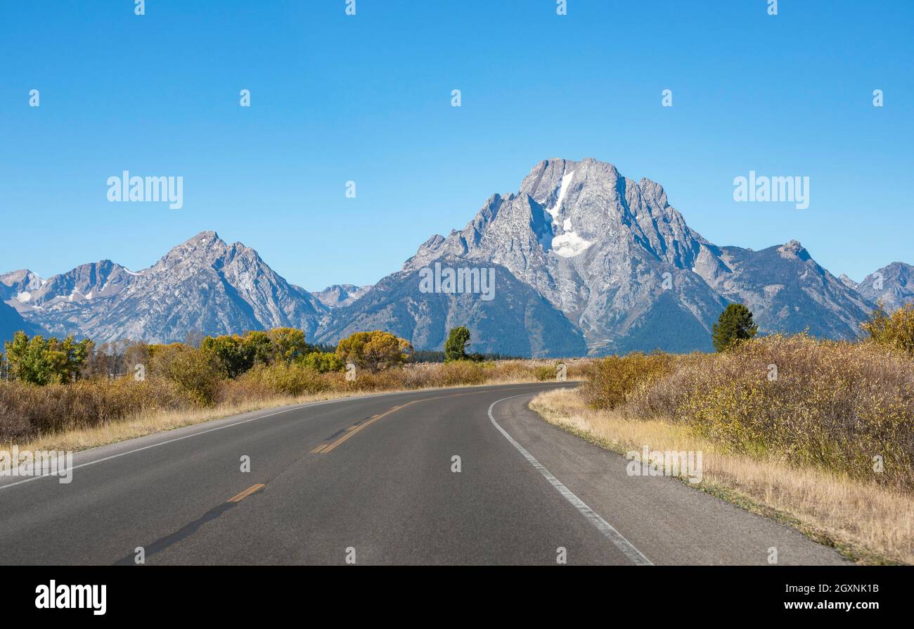 Country road through autumn landscape, Mount Moran mountain peak, Teton Range mountain range, Grand Teton National Park, Wyoming, USA Stock Photo