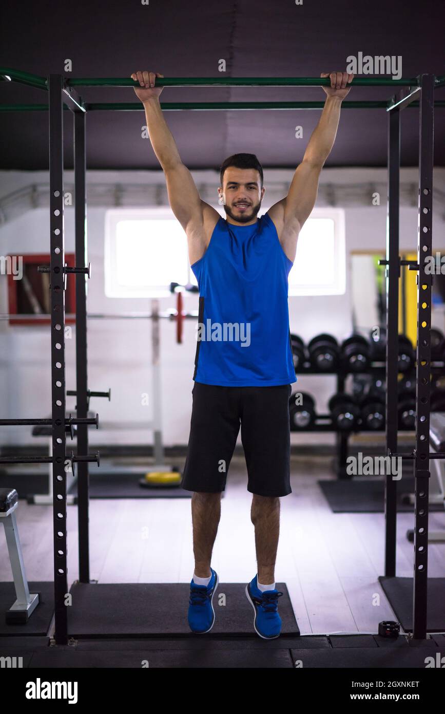 young muscular man doing pull ups on the horizontal bar as part of ...