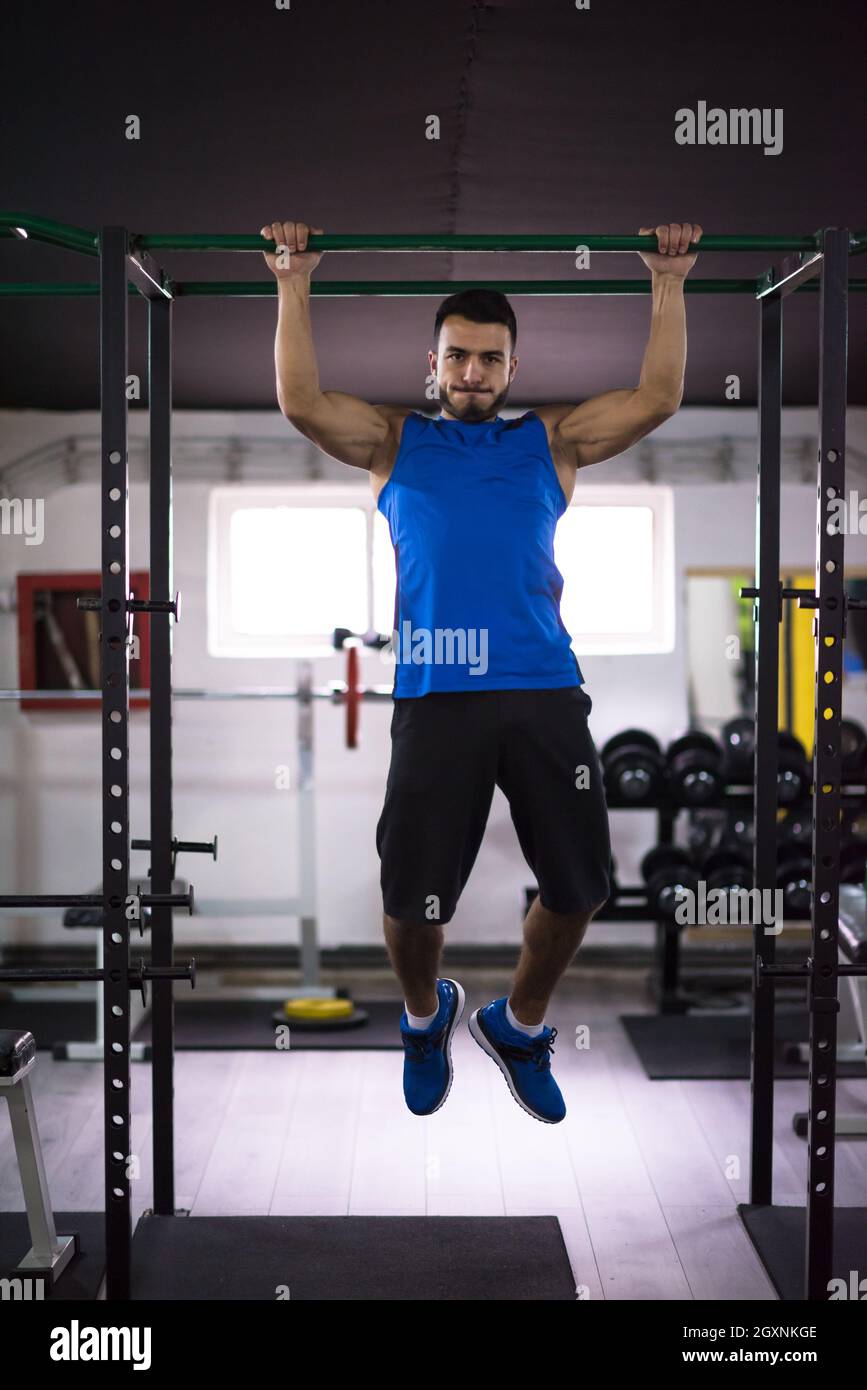 young muscular man doing pull ups on the horizontal bar as part of ...