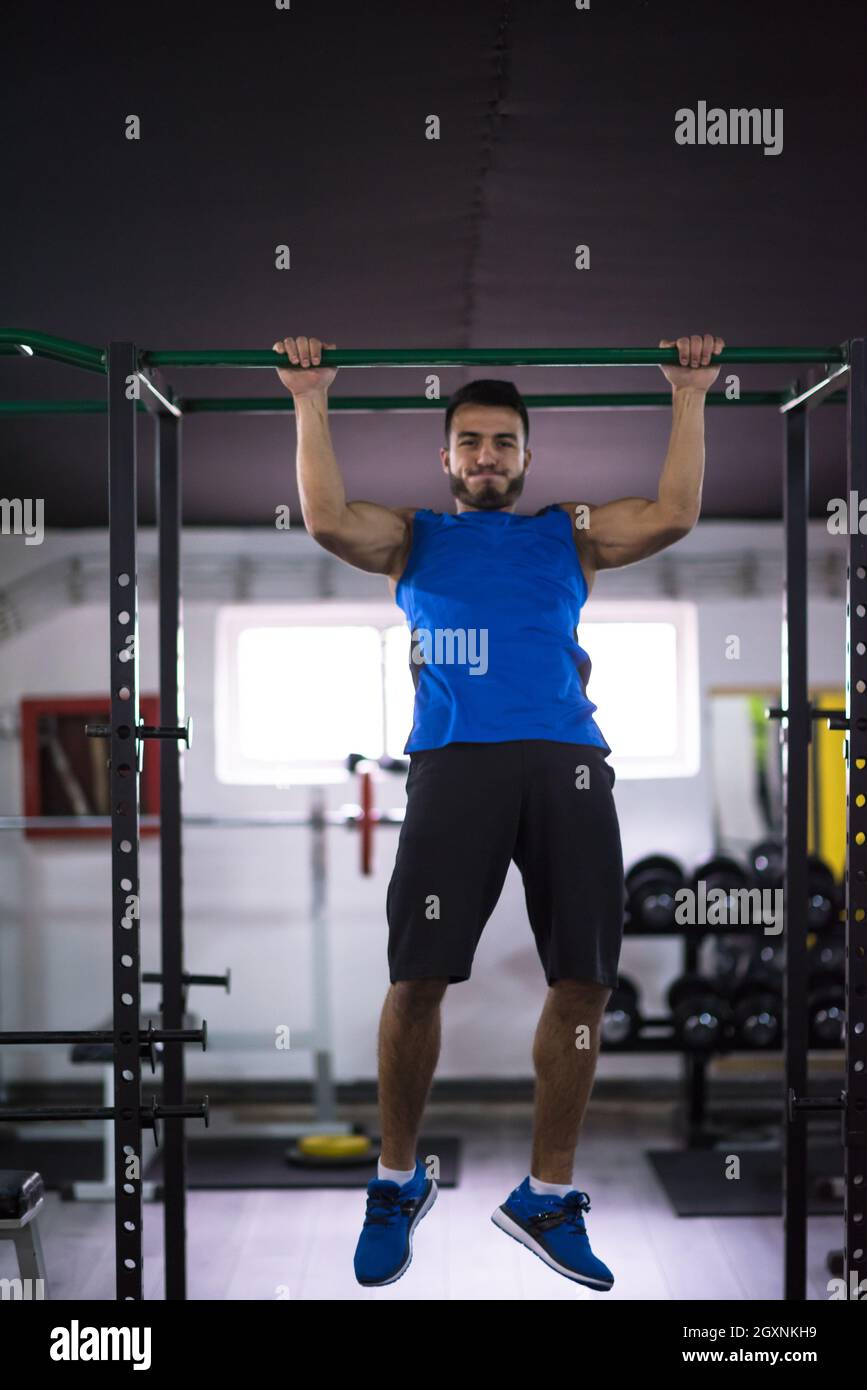young muscular man doing pull ups on the horizontal bar as part of ...