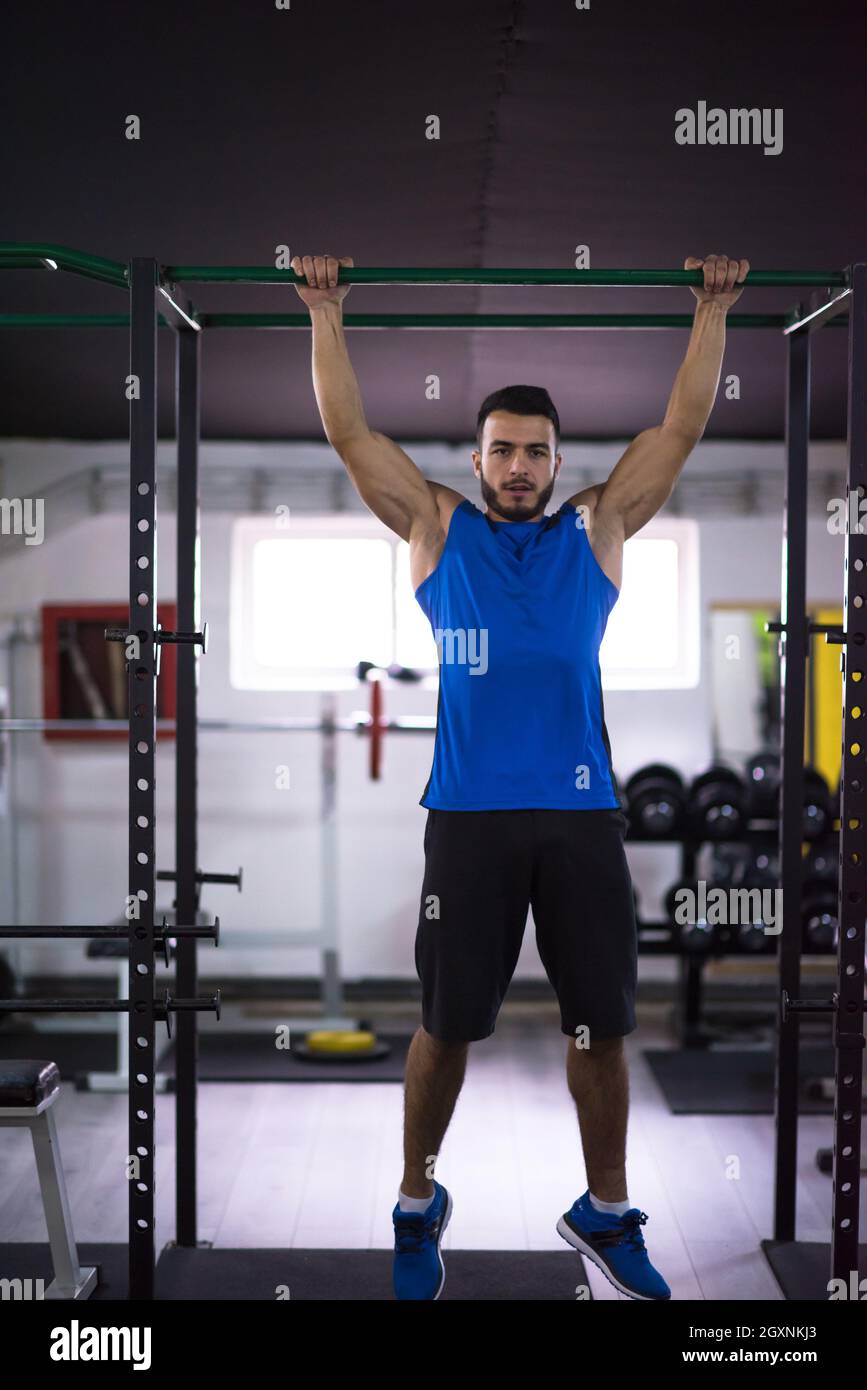 young muscular man doing pull ups on the horizontal bar as part of ...