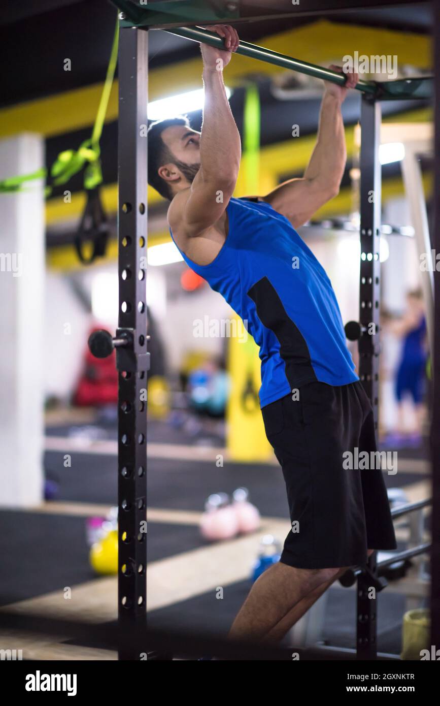 young muscular man doing pull ups on the horizontal bar as part of ...