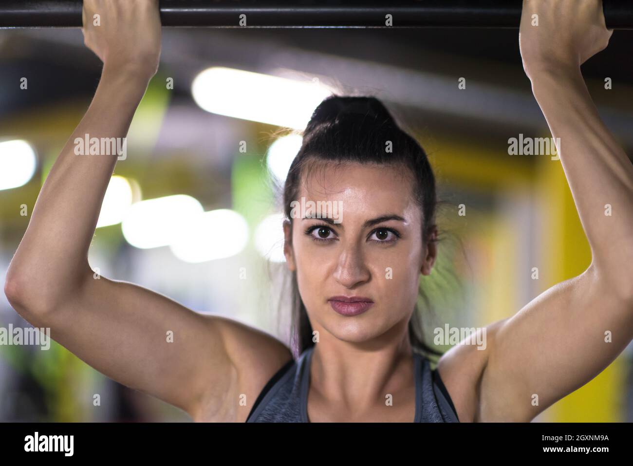 young muscular woman doing pull ups on the horizontal bar as part of ...