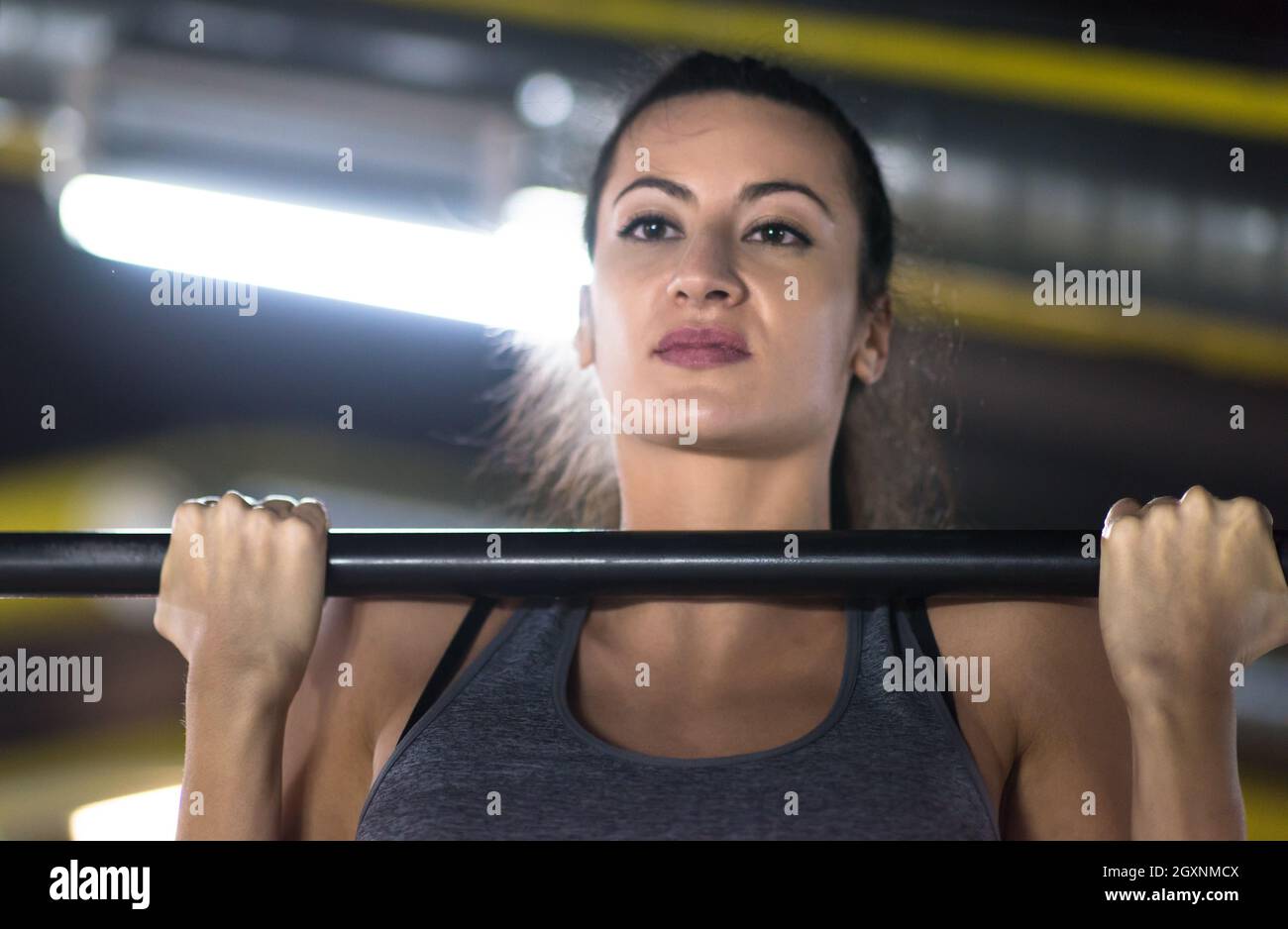 young muscular woman doing pull ups on the horizontal bar as part of ...