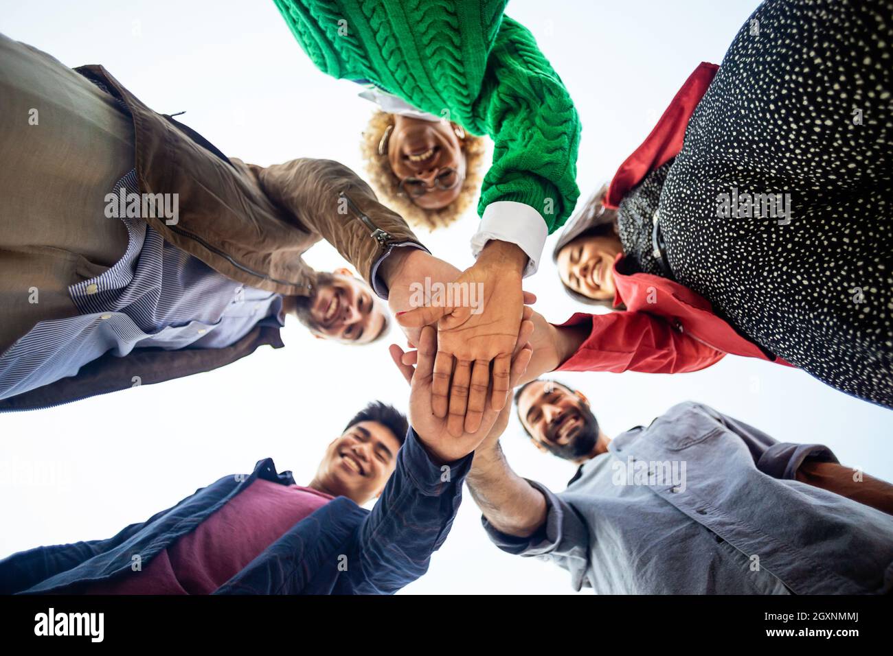 United diverse happy young people stacking hands Stock Photo