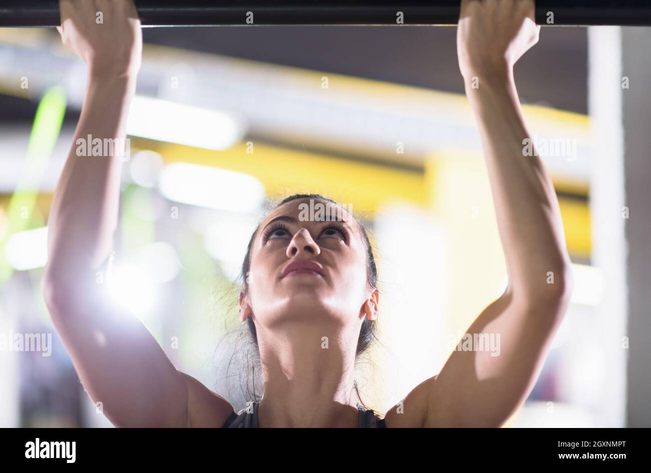 young muscular woman doing pull ups on the horizontal bar as part of ...