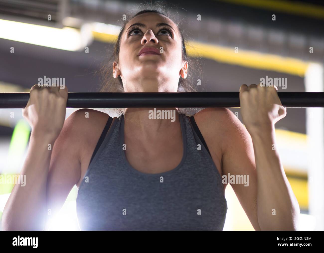 young muscular woman doing pull ups on the horizontal bar as part of ...