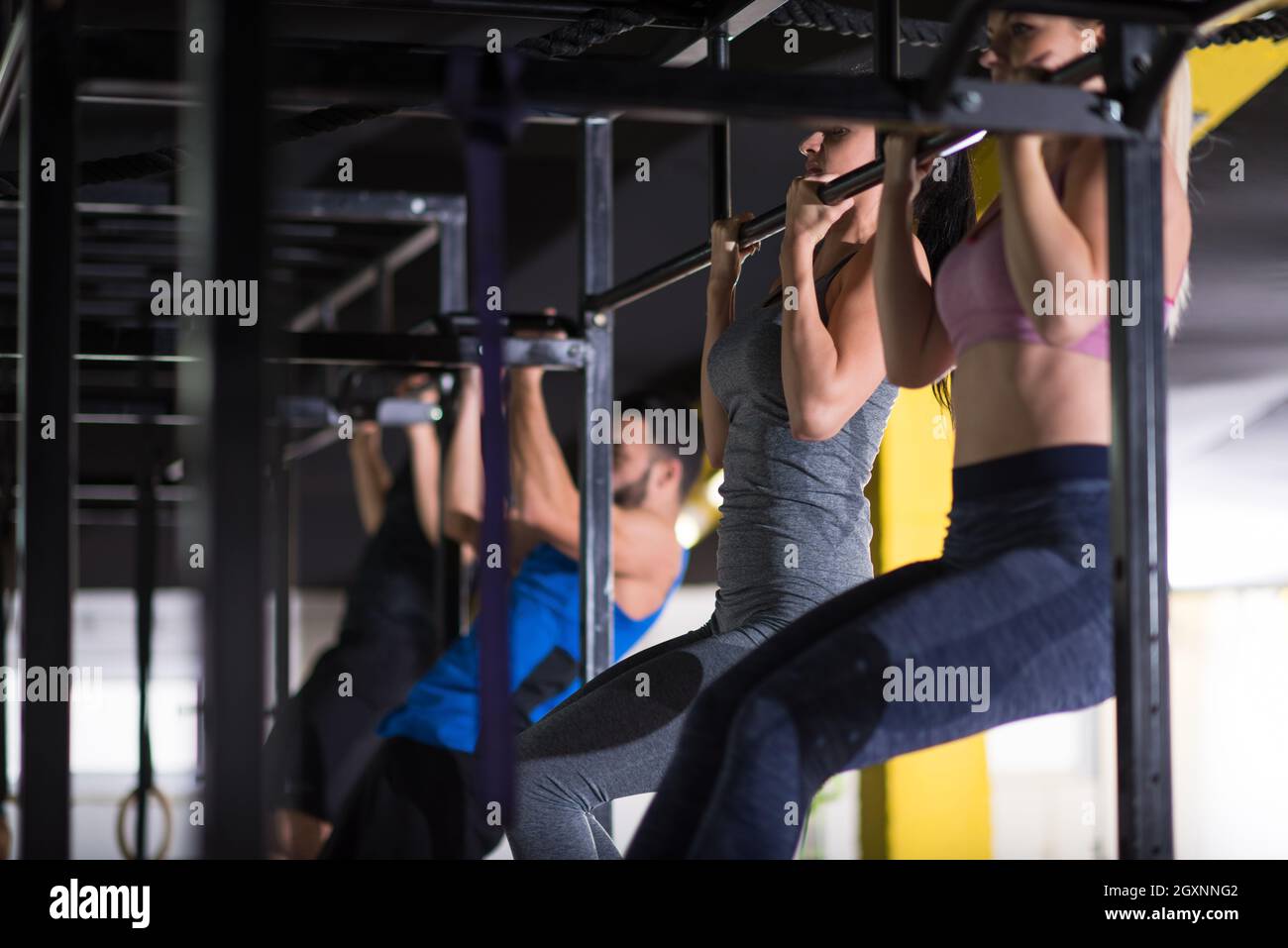 group of young muscular athletes doing pull ups on the horizontal bar ...