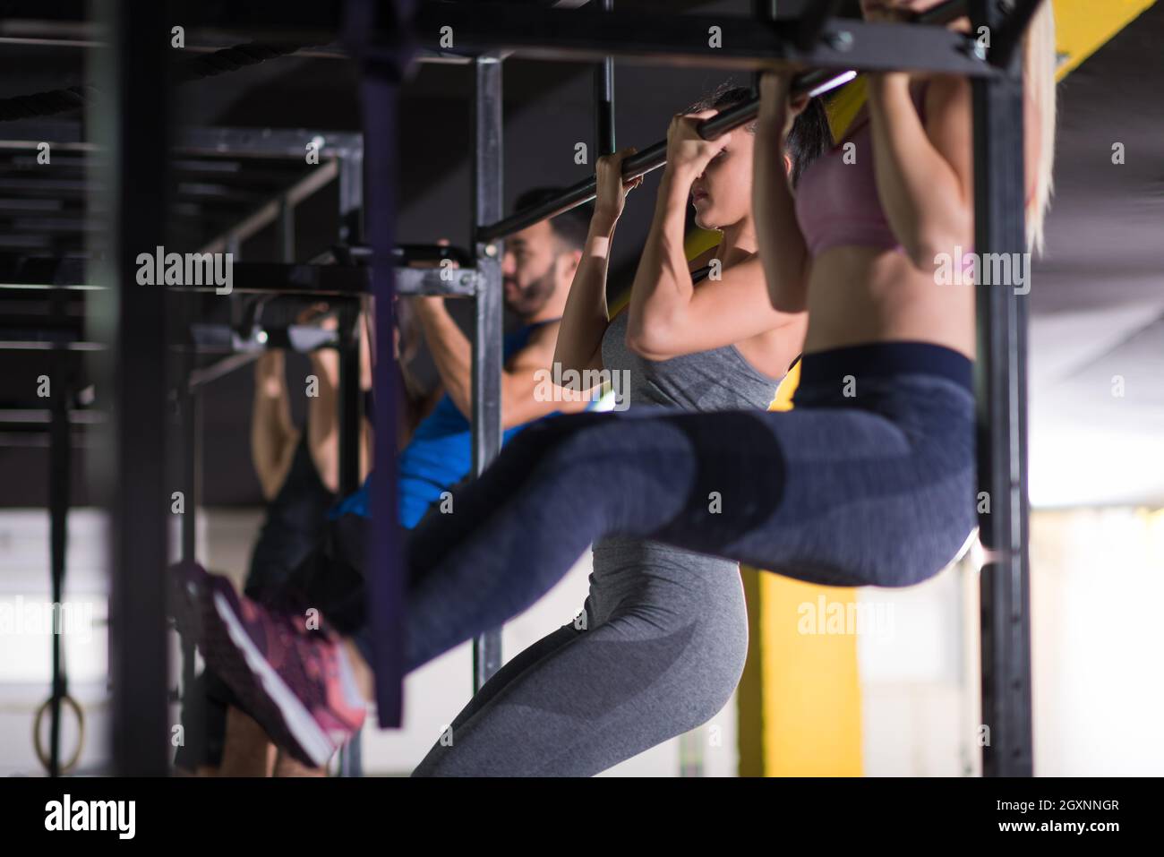 group of young muscular athletes doing pull ups on the horizontal bar ...
