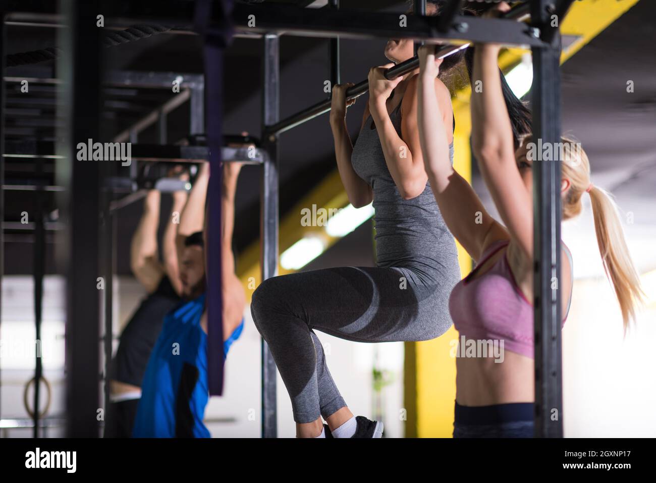 group of young muscular athletes doing pull ups on the horizontal bar ...