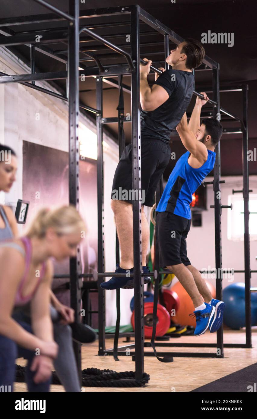 group of young muscular athletes doing pull ups on the horizontal bar ...