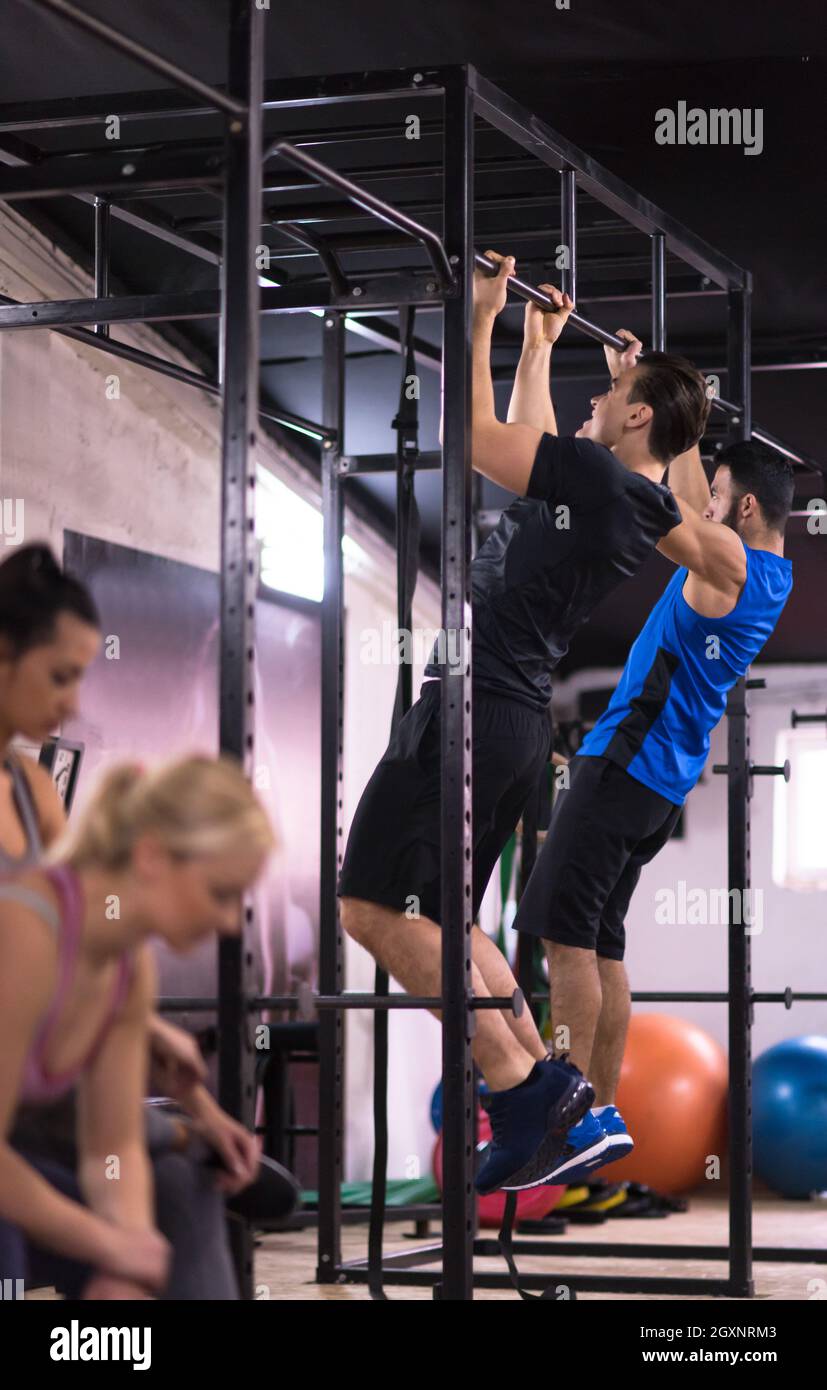 group of young muscular athletes doing pull ups on the horizontal bar ...