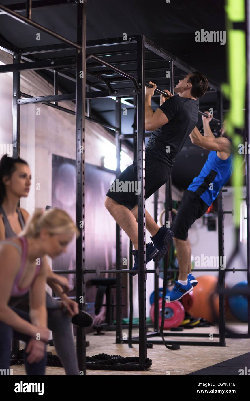 group of young muscular athletes doing pull ups on the horizontal bar ...