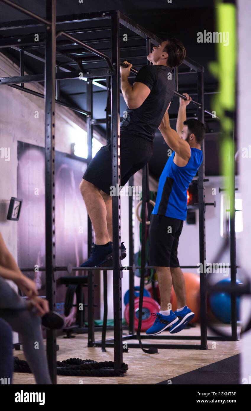 group of young muscular athletes doing pull ups on the horizontal bar ...