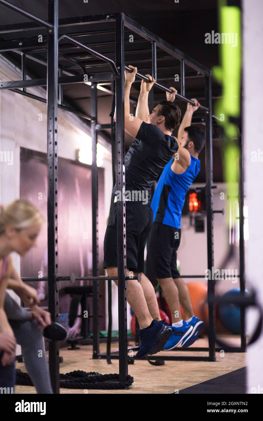 group of young muscular athletes doing pull ups on the horizontal bar ...