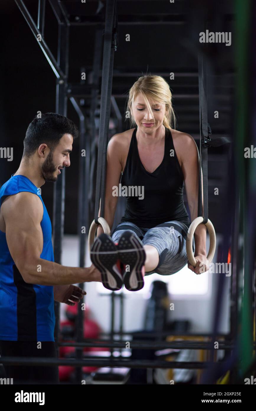 young athletic woman working out with personal trainer on gymnastic