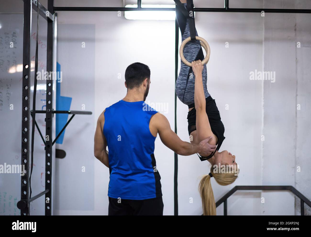 young athletic woman working out with personal trainer on gymnastic
