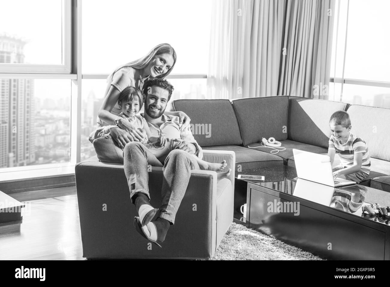 happy couple spending time with kids using tablet computer on an armchair  at home Stock Photo
