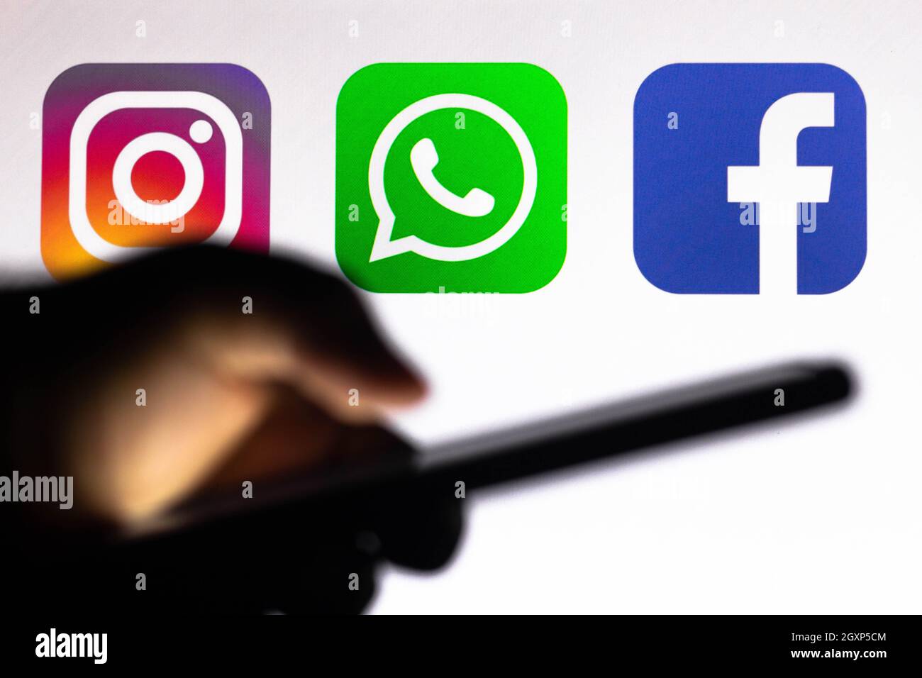 In this photo illustration the Instagram, WhatsApp and Facebook logo app  seen in the background of a silhouette hand holding a mobile phone Stock  Photo - Alamy