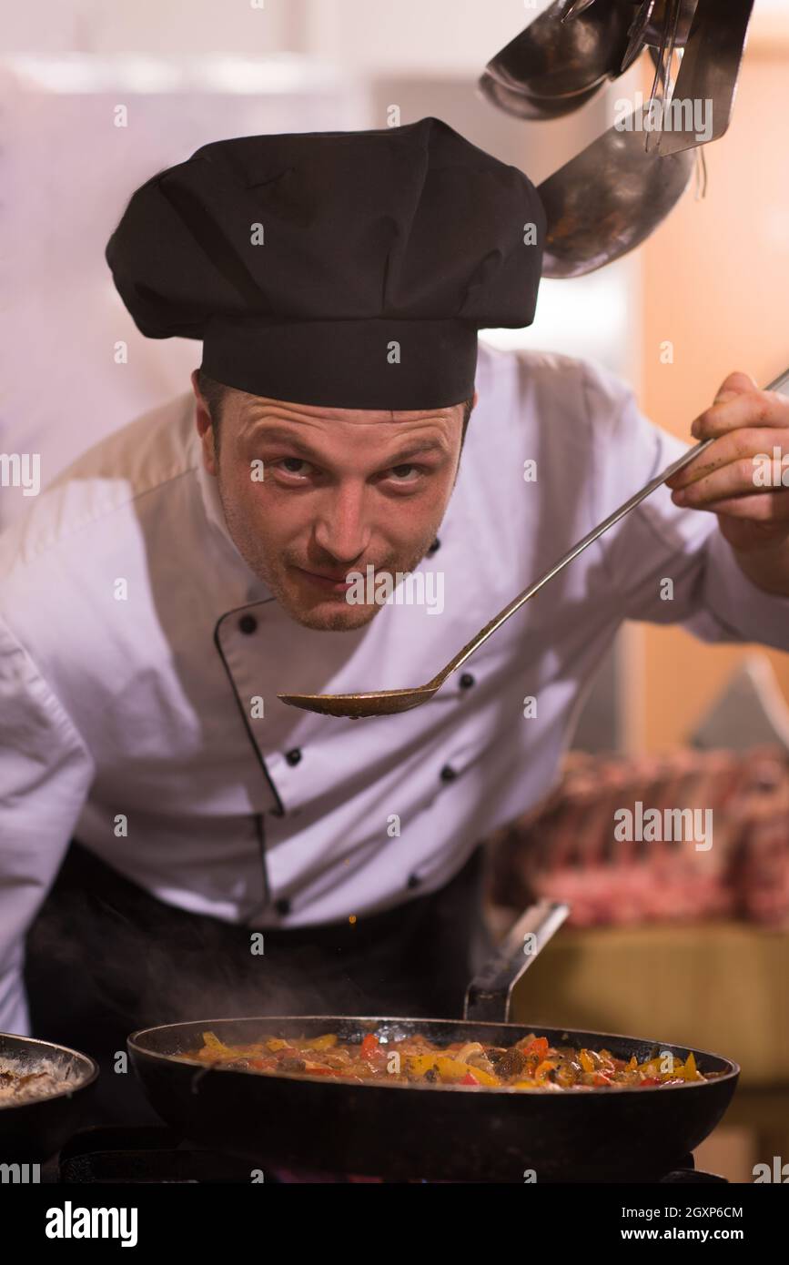 Handsome chef tasting food with spoon at the restaurant kitchen Stock ...