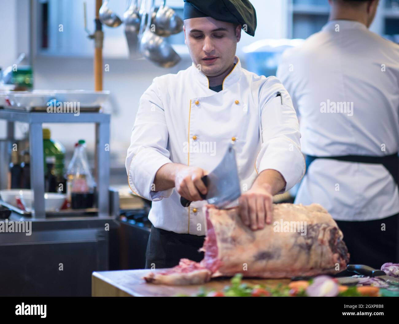 chef using ax while cutting big piece of beef on wooden board in ...