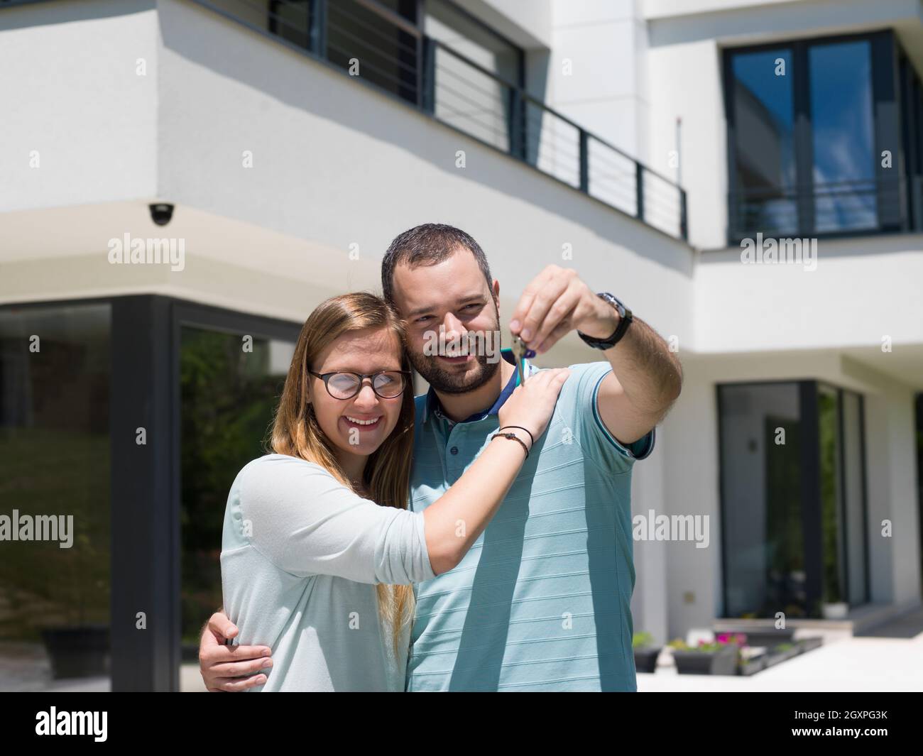 Portrait of a happy young couple hugging in front of their new luxury ...