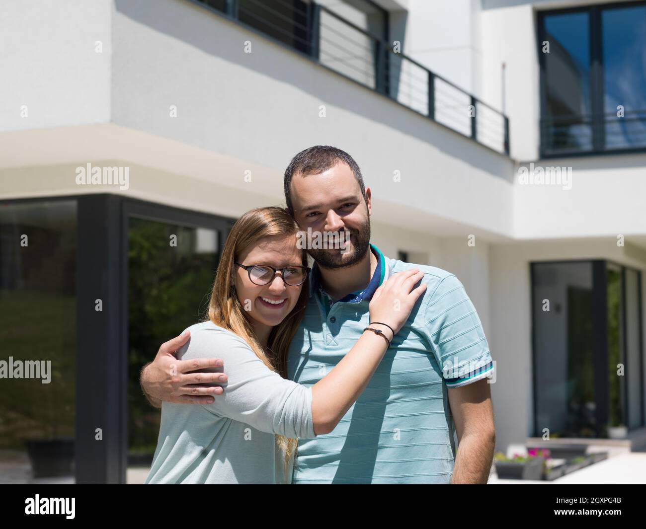 Portrait of a happy young couple hugging in front of their new luxury ...