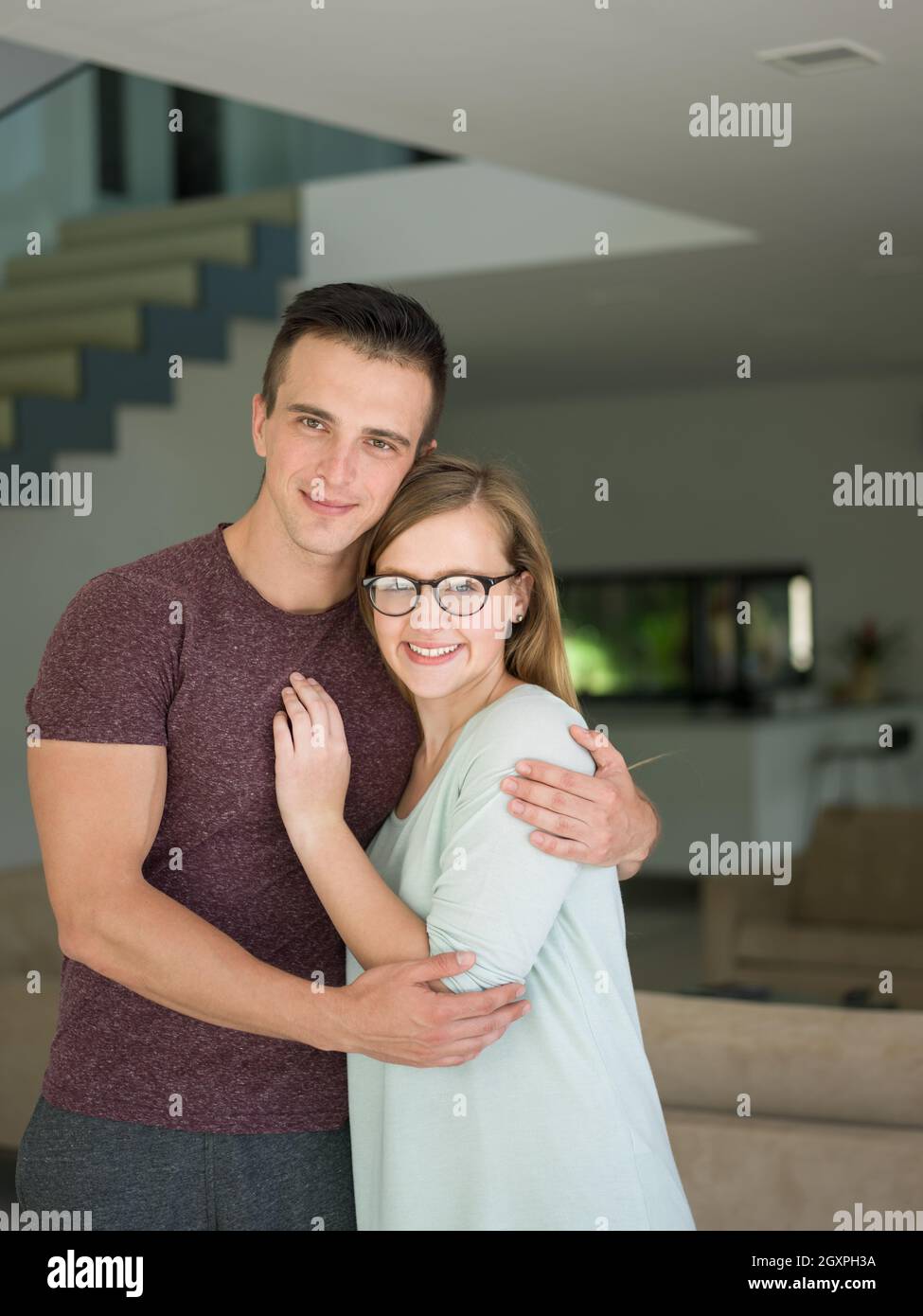 Portrait of a happy young beautiful couple hugging in their new home ...