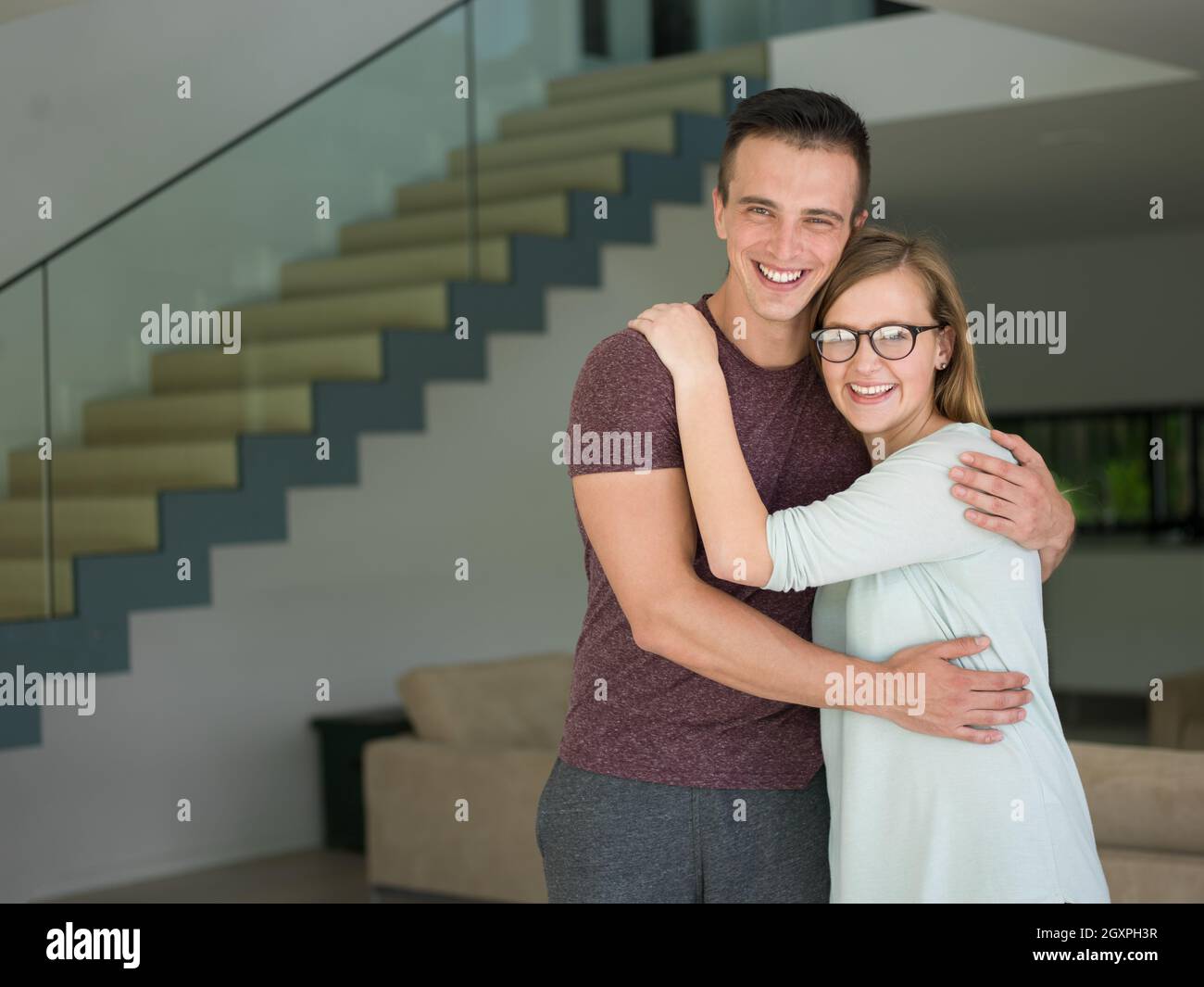 Portrait of a happy young beautiful couple hugging in their new home ...