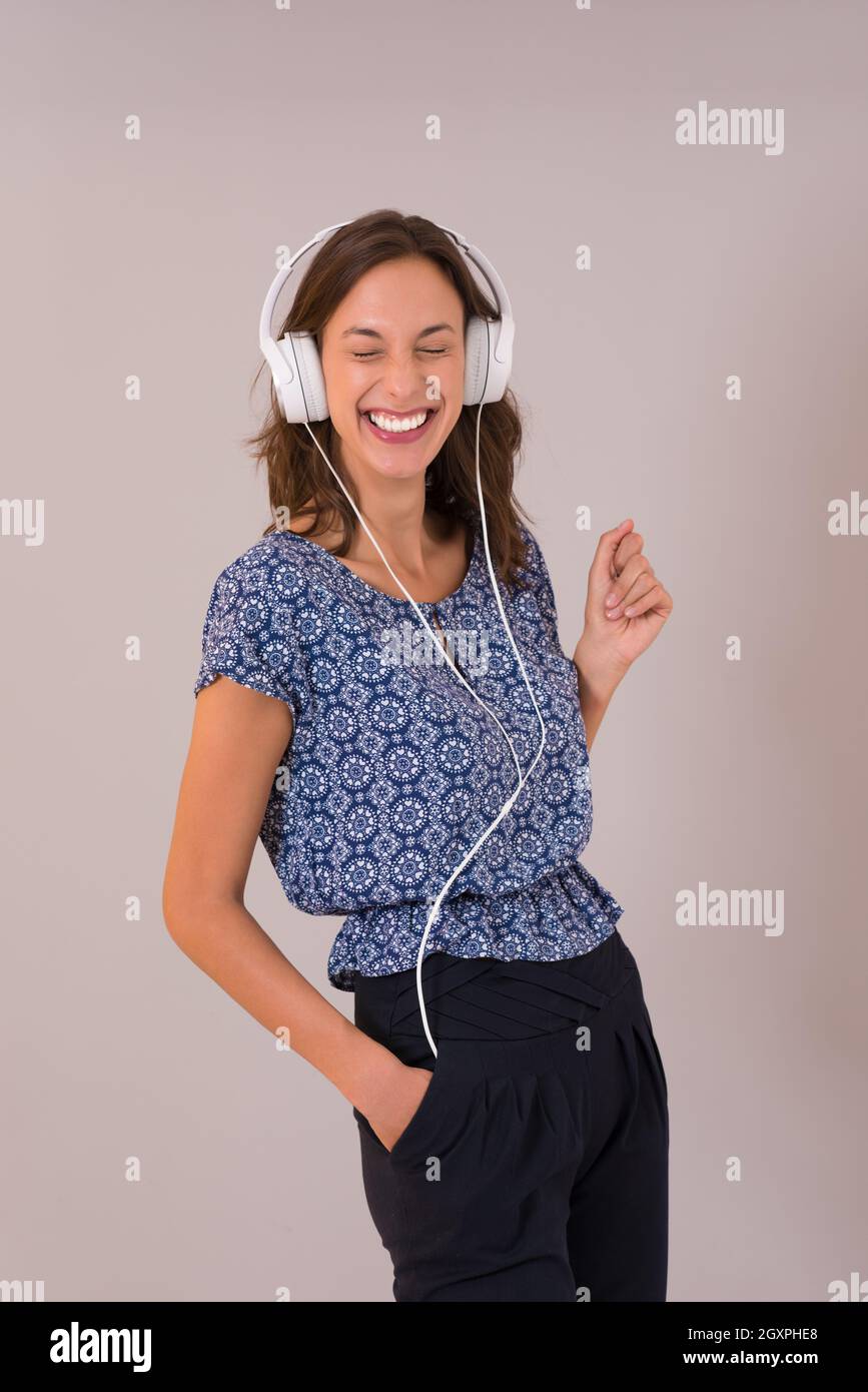 Happy young woman listening and enjoying music with headphones isolated ...