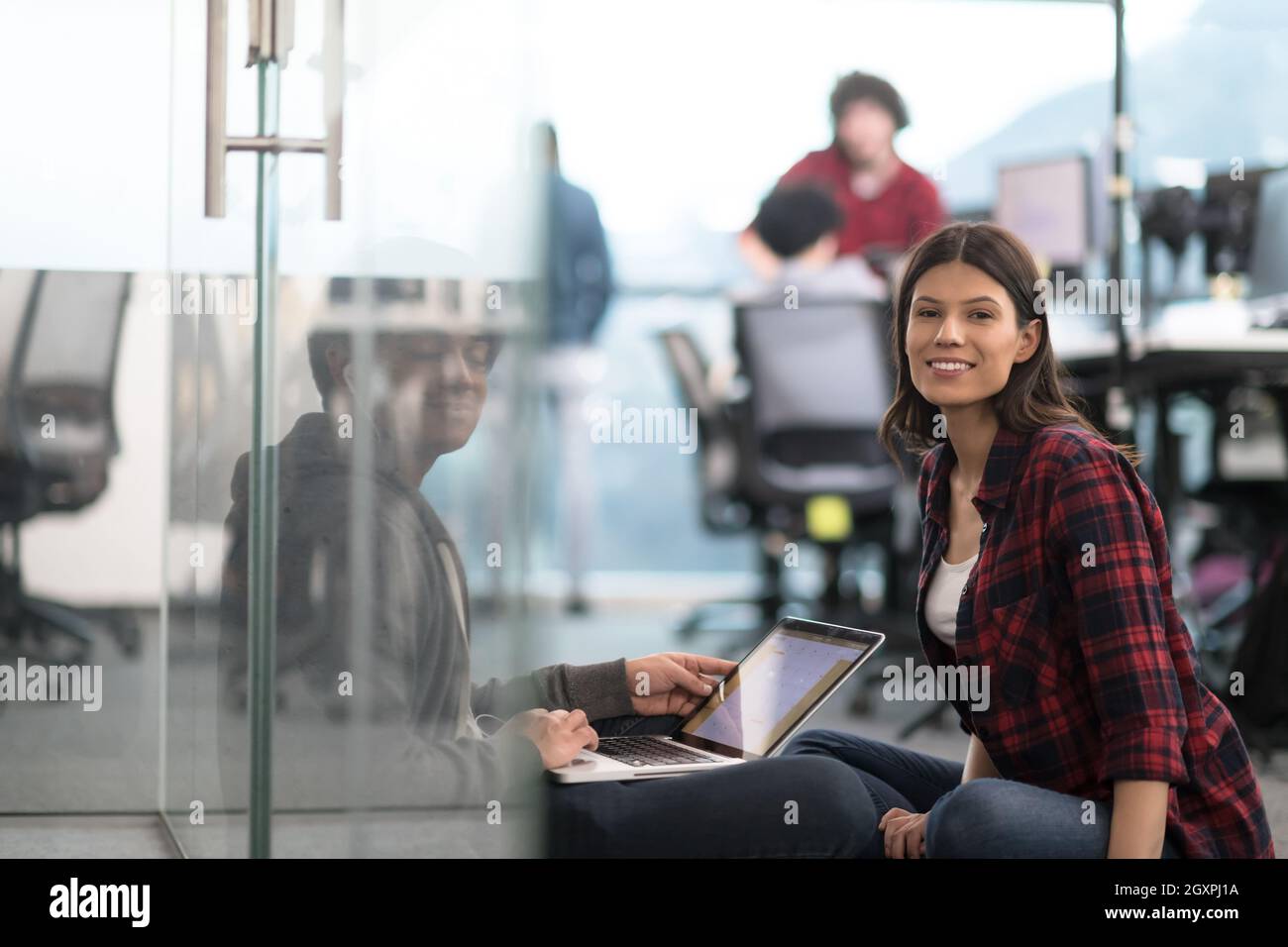 young software developers couple using laptop computer writing programming code while sitting on the floor at modern creative startup office Stock Photo
