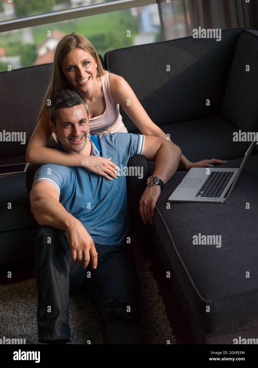 Attractive couple using a laptop in the living room Stock Photo - Alamy