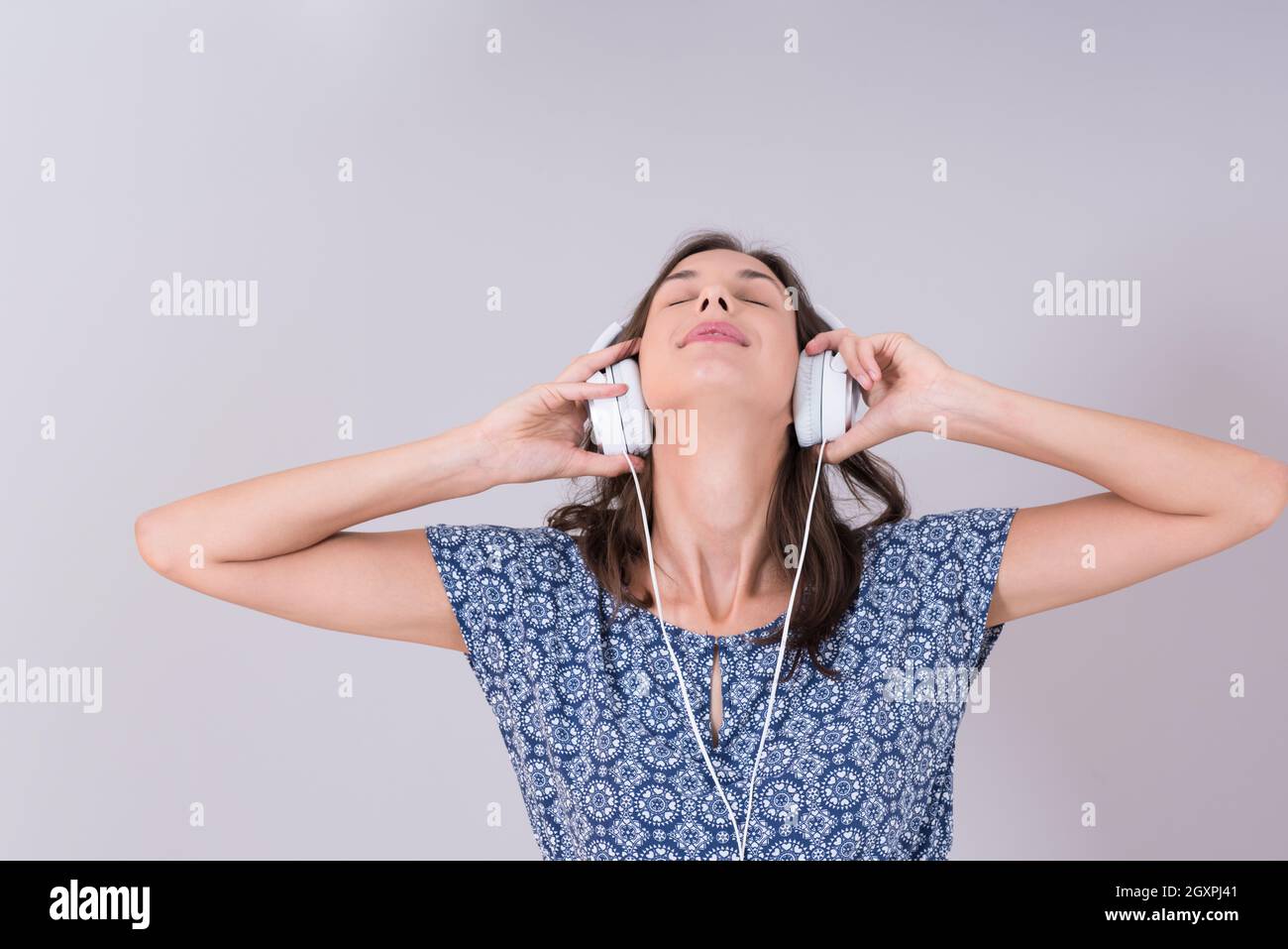 Happy young woman listening and enjoying music with headphones isolated ...