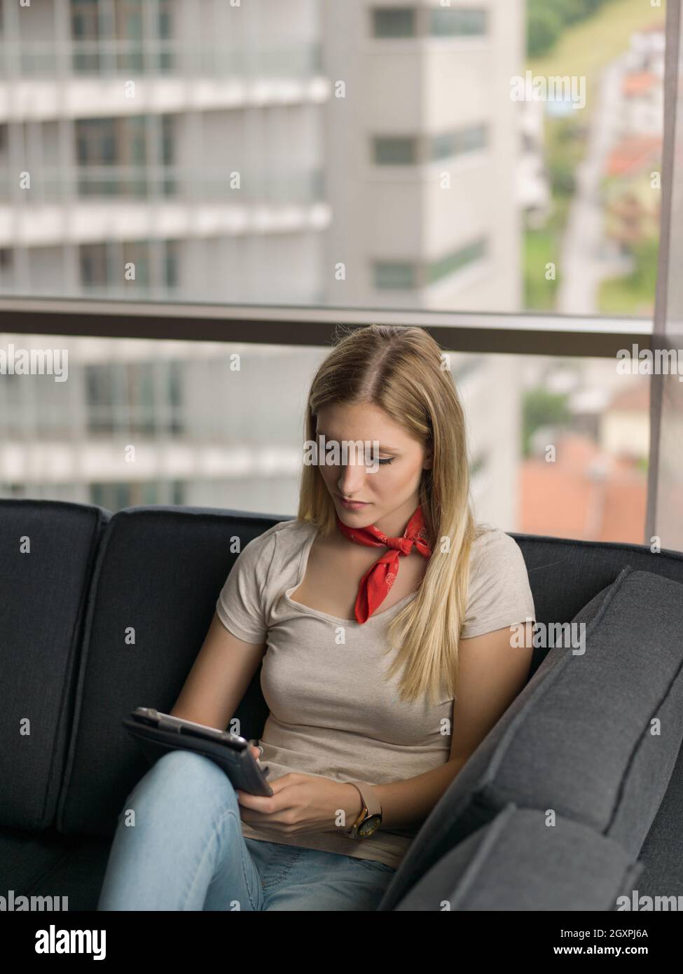 beautiful young woman on sofa at home surfing internet using tablet ...