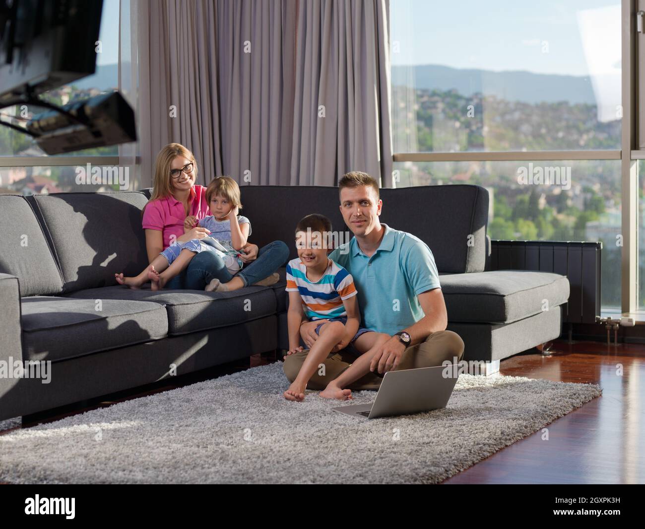 young happy family relaxing at home using laptop and tablet computers ...
