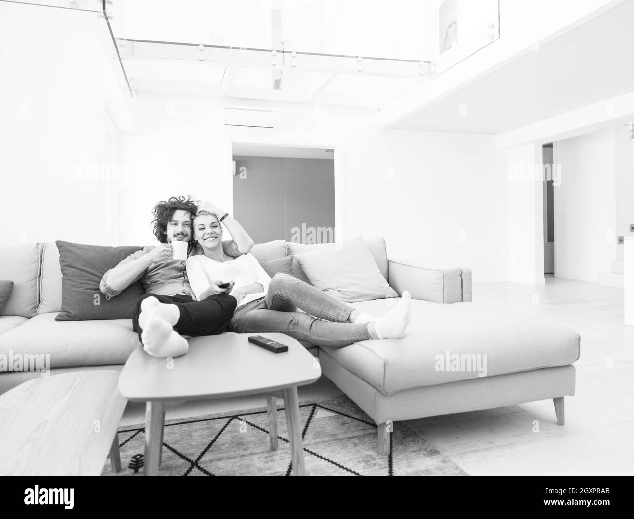Young couple on the sofa watching television together in their luxury home Stock Photo