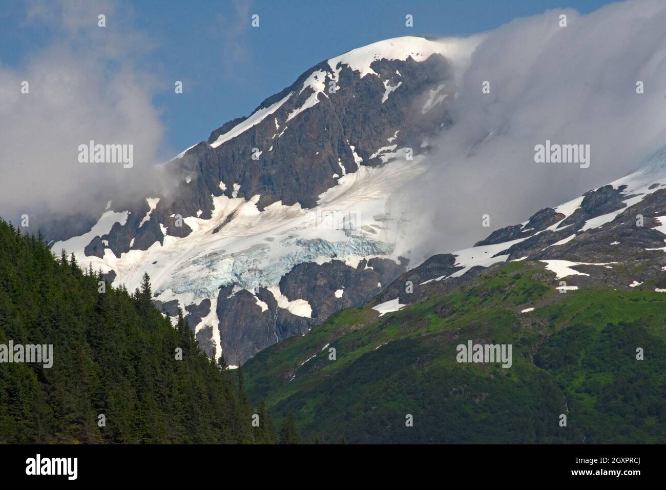 Snowcapped mountain between low clouds, Cordova, Alaska, USA Stock Photo