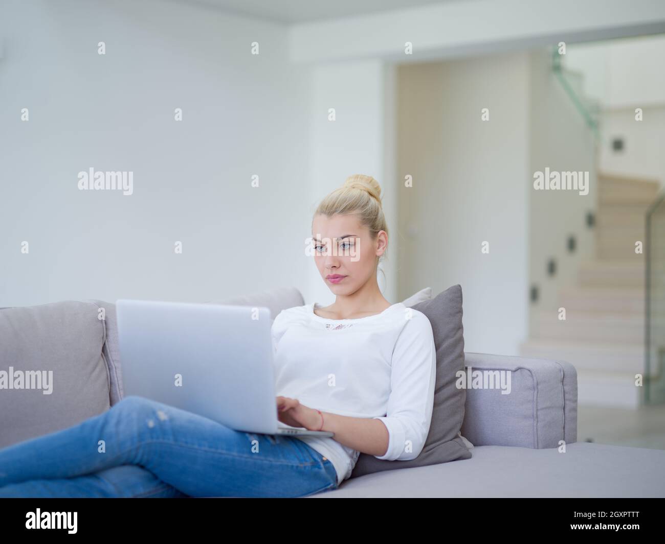Young woman using her laptop computer in her luxury modern home ...