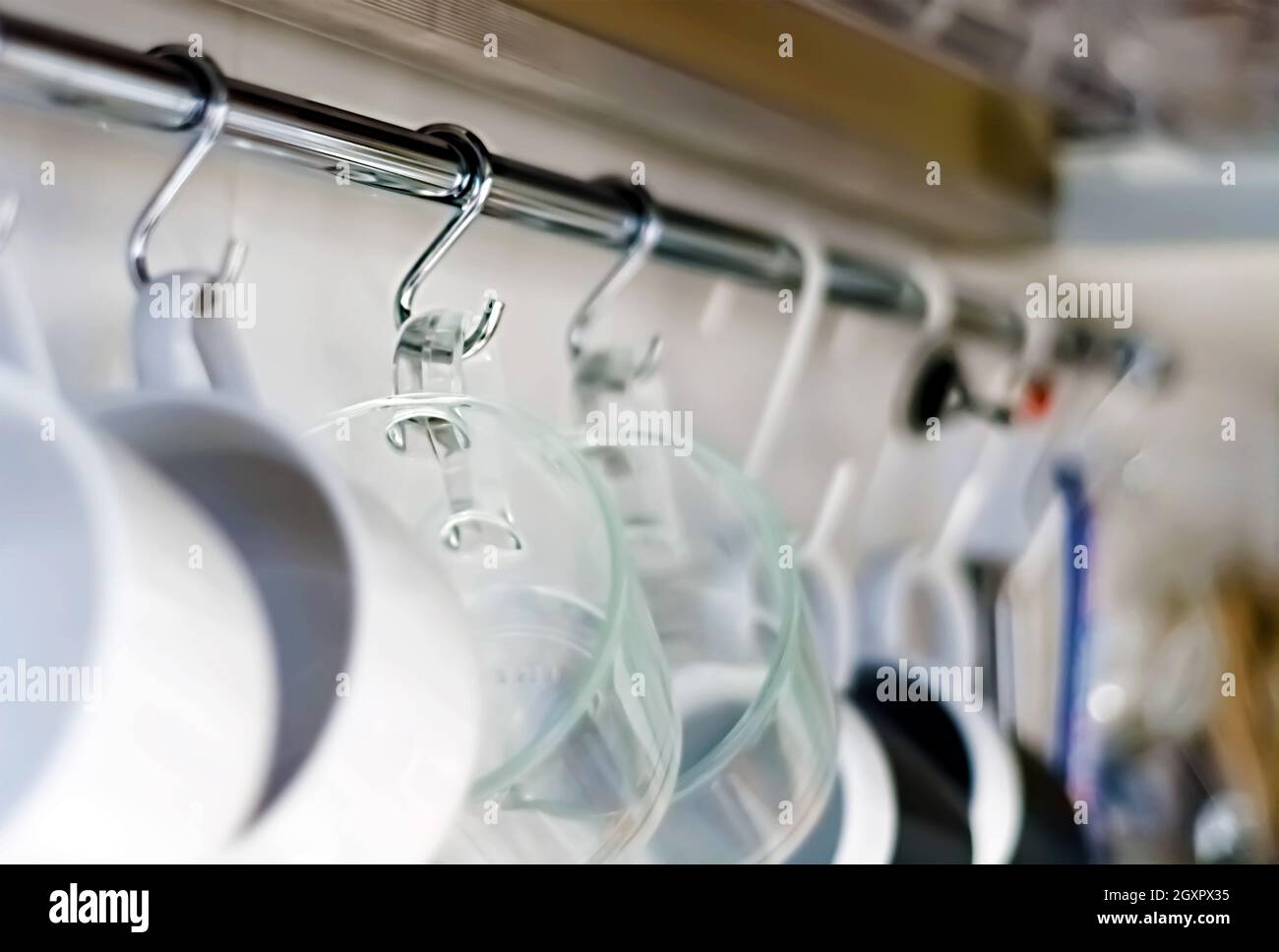 A set of mugs hanging on hooks in a modern home kitchen. Everyday objects. Domestic life. Stock Photo