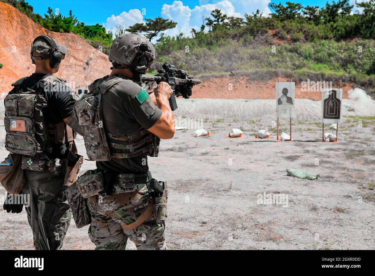 OKINAWA, Japan – A U.S. Army Green Beret with 1st Special Forces Group (Airborne) fires his M4 carbine at a target while being evaluated during pre - special forces advanced reconnaissance, target analysis, and exploitation techniques course (SFARTAETC) on Sept. 24, 2021. SFARTAETC teaches combat weapons marksmanship, close quarters battle (CQB) and explosive and mechanical breaching in preparation for real world crises response scenarios. (This photo has been altered for security purposes) Stock Photo
