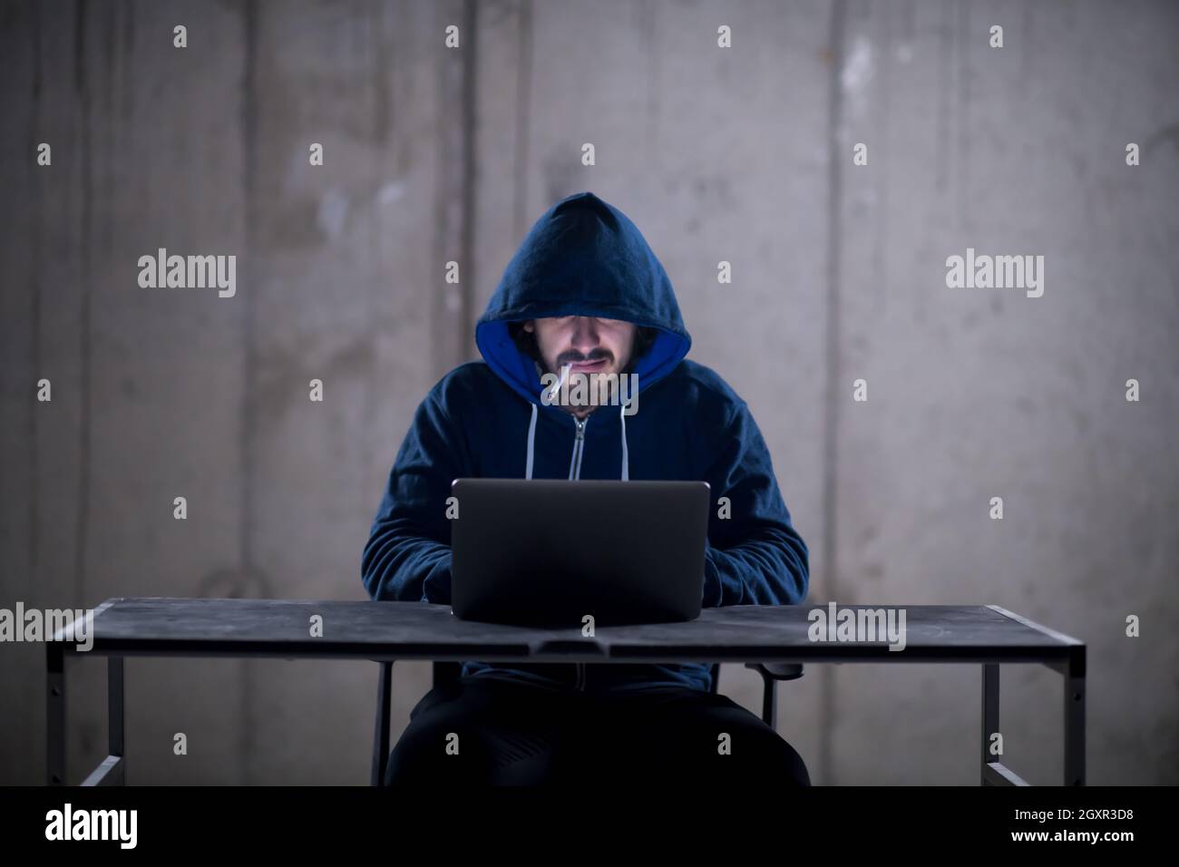 Young talented hacker smoking cigarette while working on laptop