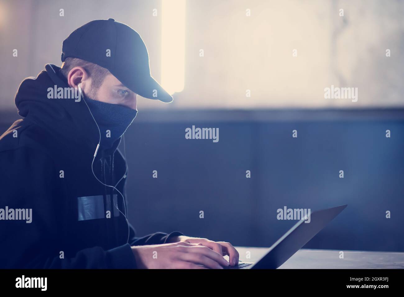 Young talented hacker using laptop computer while working in dark ...