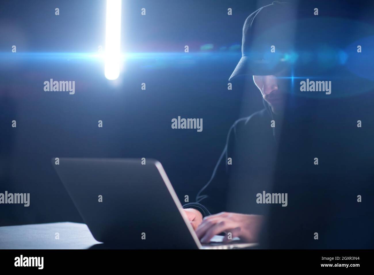Young talented hacker using laptop computer while working in dark ...